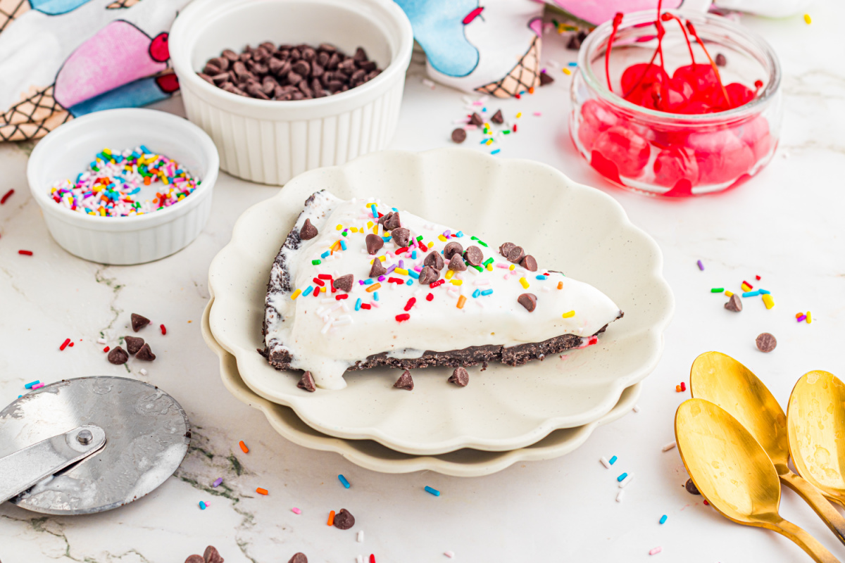 slice of ice cream pizza on a plate with Oreo crust, sprinkles, and chocolate chips
