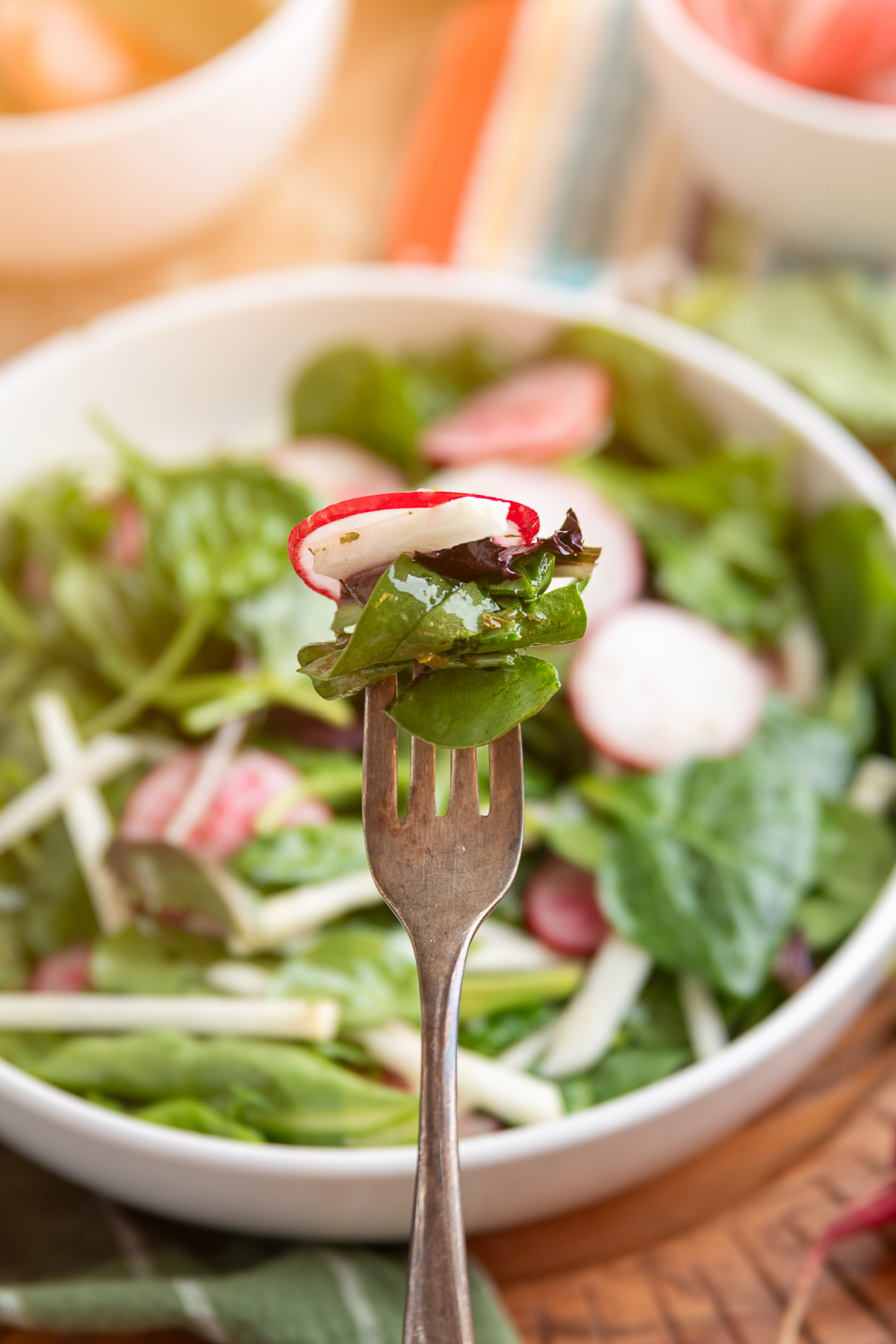 jicama radish salad on a fork with mixed greens and thinly sliced radishes