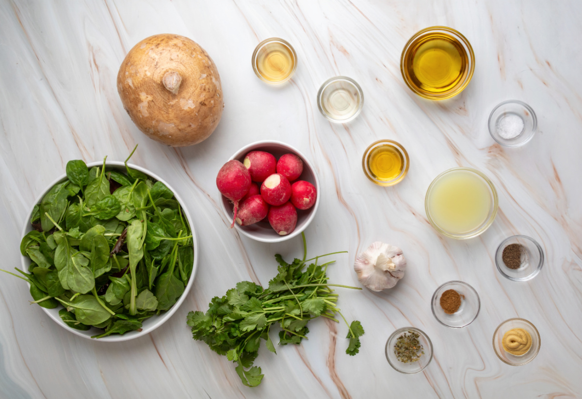 ingredients for jicama radish salad with lime vinaigrette including greens, radishes, jicama, and cilantro
