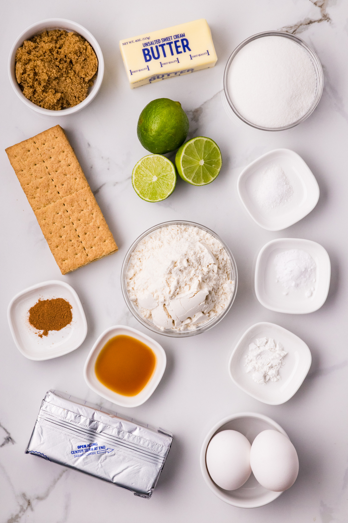 ingredients for lime cookies including graham crackers, fresh limes, butter, flour, sugar, and eggs