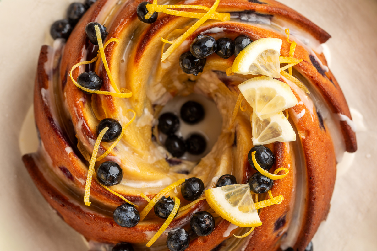 lemon blueberry sour cream bundt cake from above with lemon glaze, blueberries, and lemon zest