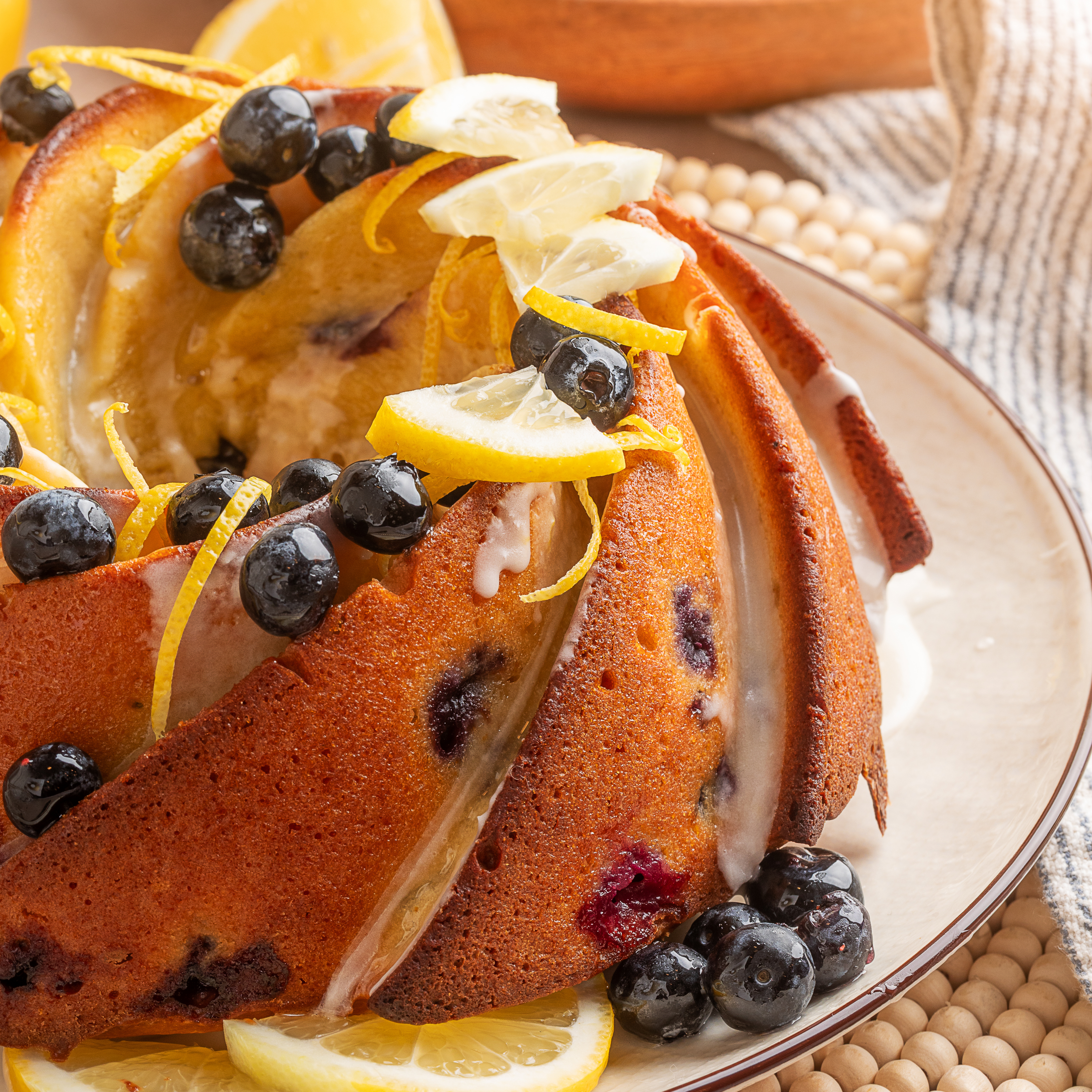 Lemon blueberry sour cream bundt cake with lemon glaze, fresh blueberries, and lemon slices