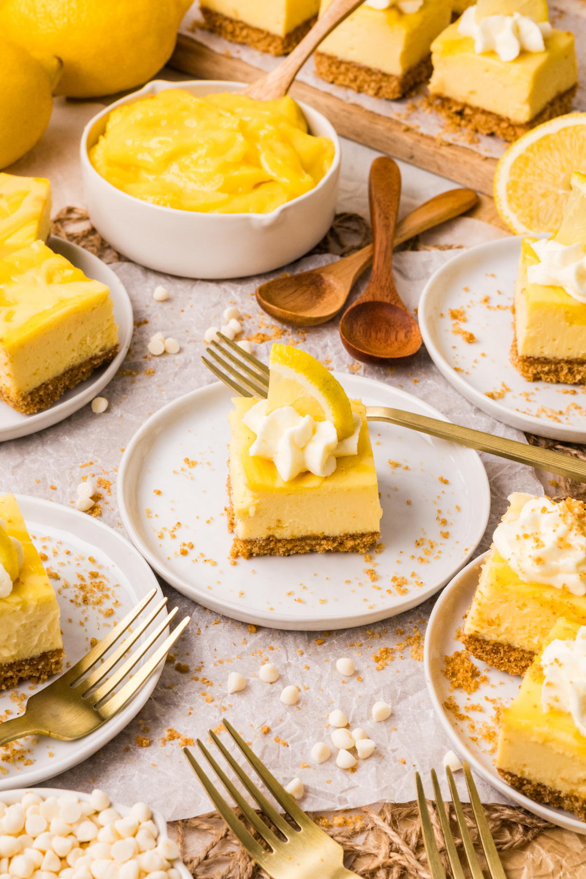 lemon cheesecake bars served on plates with lemon slices whipped cream and lemon curd