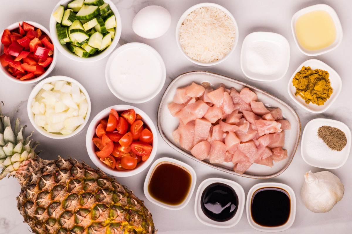 ingredients for pineapple chicken and coconut rice including chicken, pineapple, jasmine rice, vegetables, and sauces