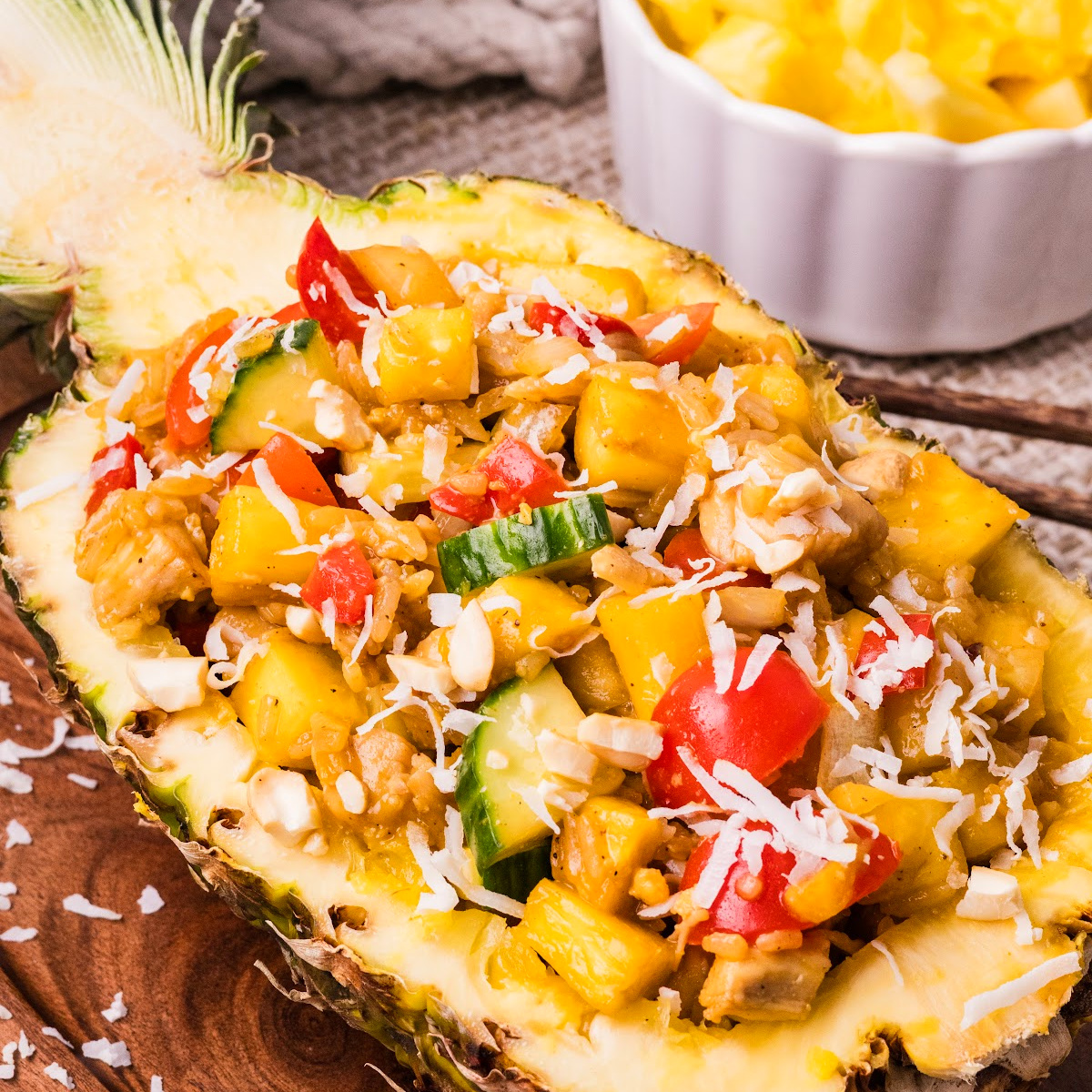 pineapple chicken and rice served in a pineapple bowl with coconut rice, chicken, and vegetables