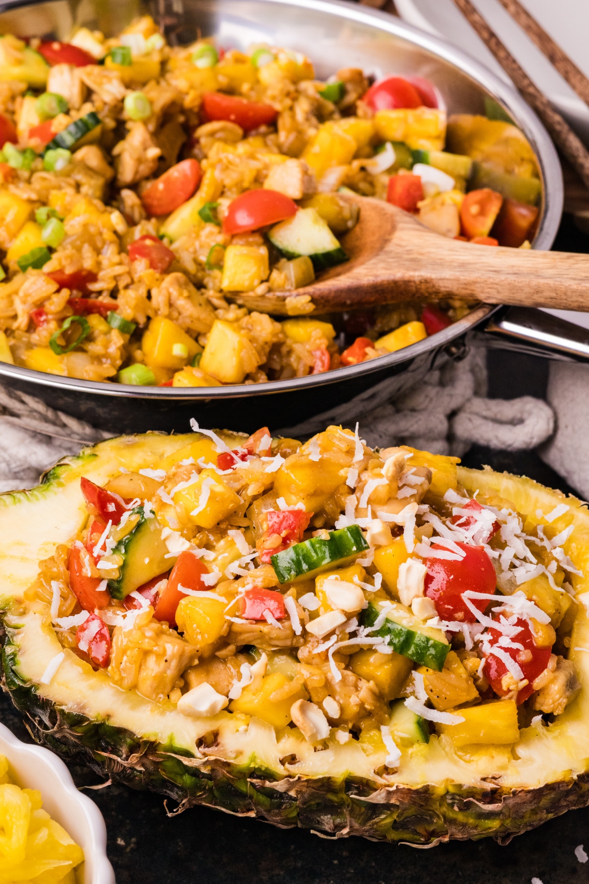 pineapple chicken and rice served in a fresh pineapple bowl with coconut rice, chicken, and vegetables