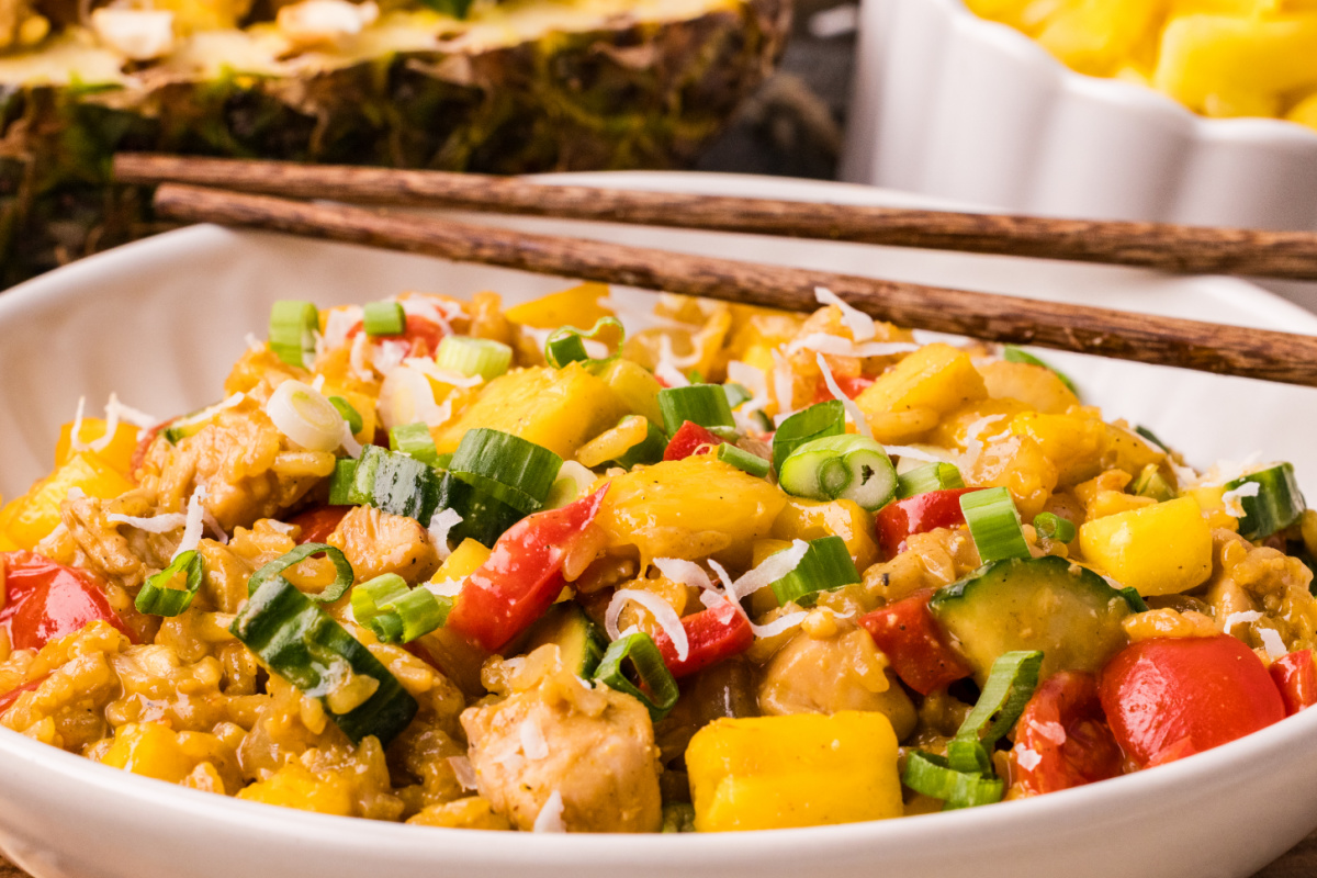 pineapple chicken fried rice with coconut rice, chicken, pineapple, and green onions in a bowl