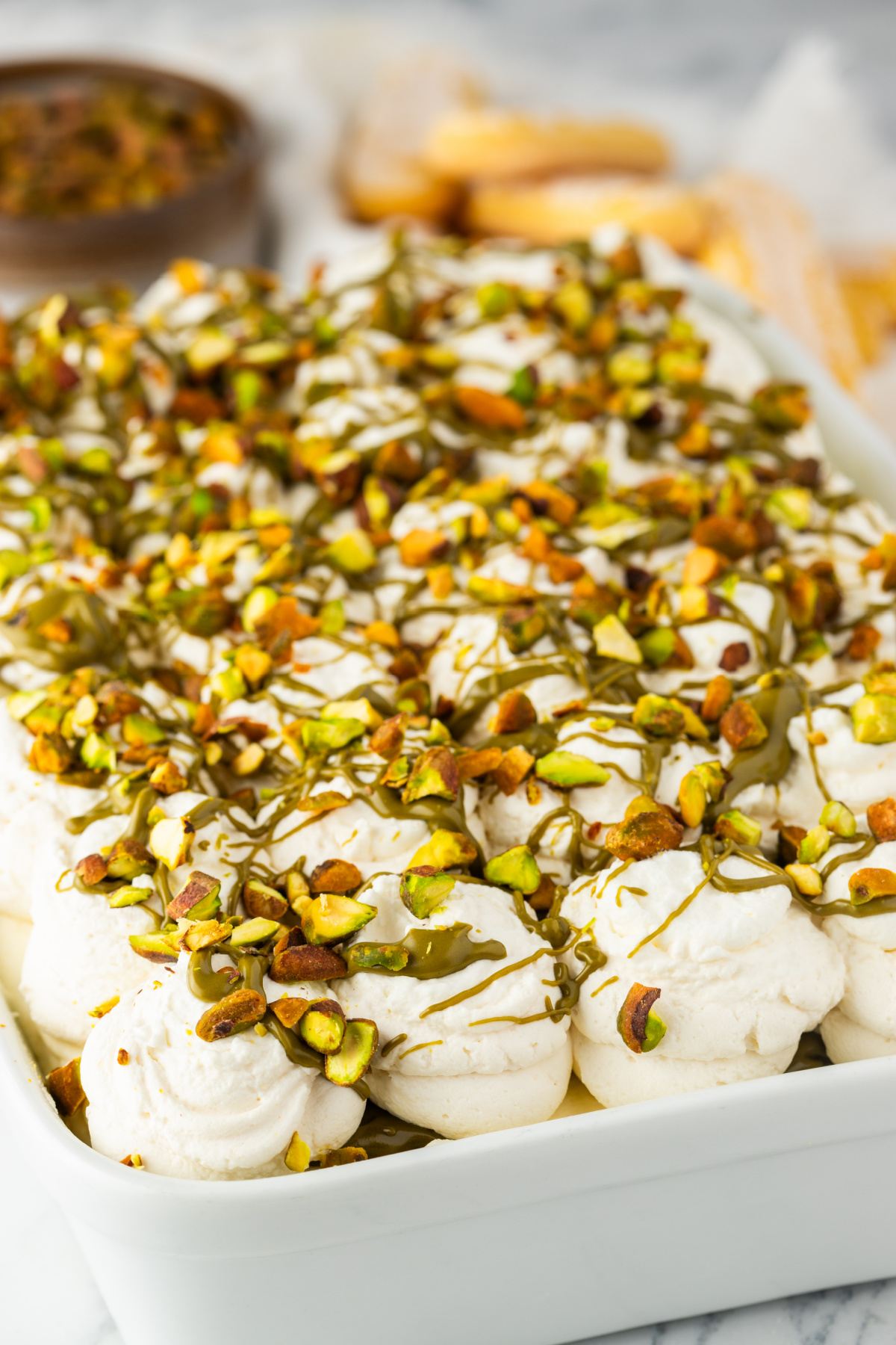 pistachio tiramisu with piped whipped cream topping finished with pistachio drizzle and chopped pistachios