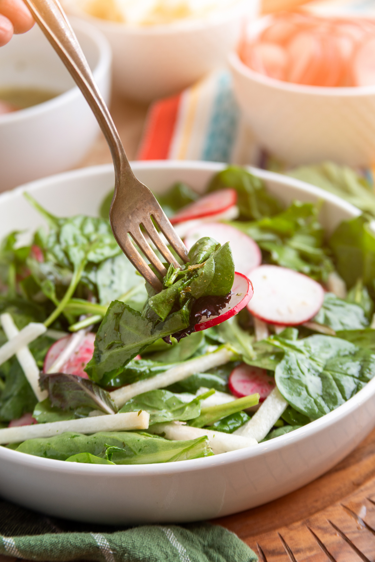 radish and jicama salad with lime vinaigrette on a fork with mixed greens and sliced radishes