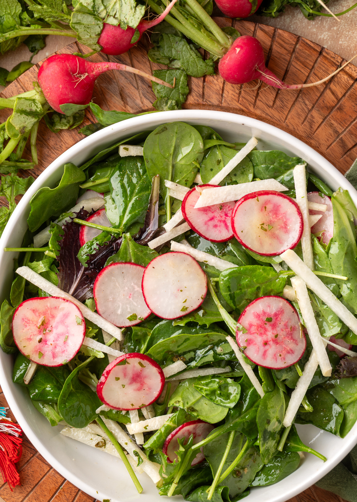 radish and jicama salad with lime vinaigrette in a white bowl with mixed greens