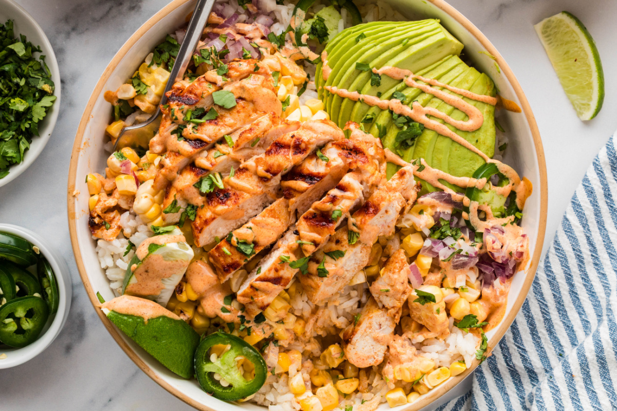 street corn chicken rice bowls with grilled chicken, avocado, charred corn, jalape&ntilde;os, and creamy elote-style sauce