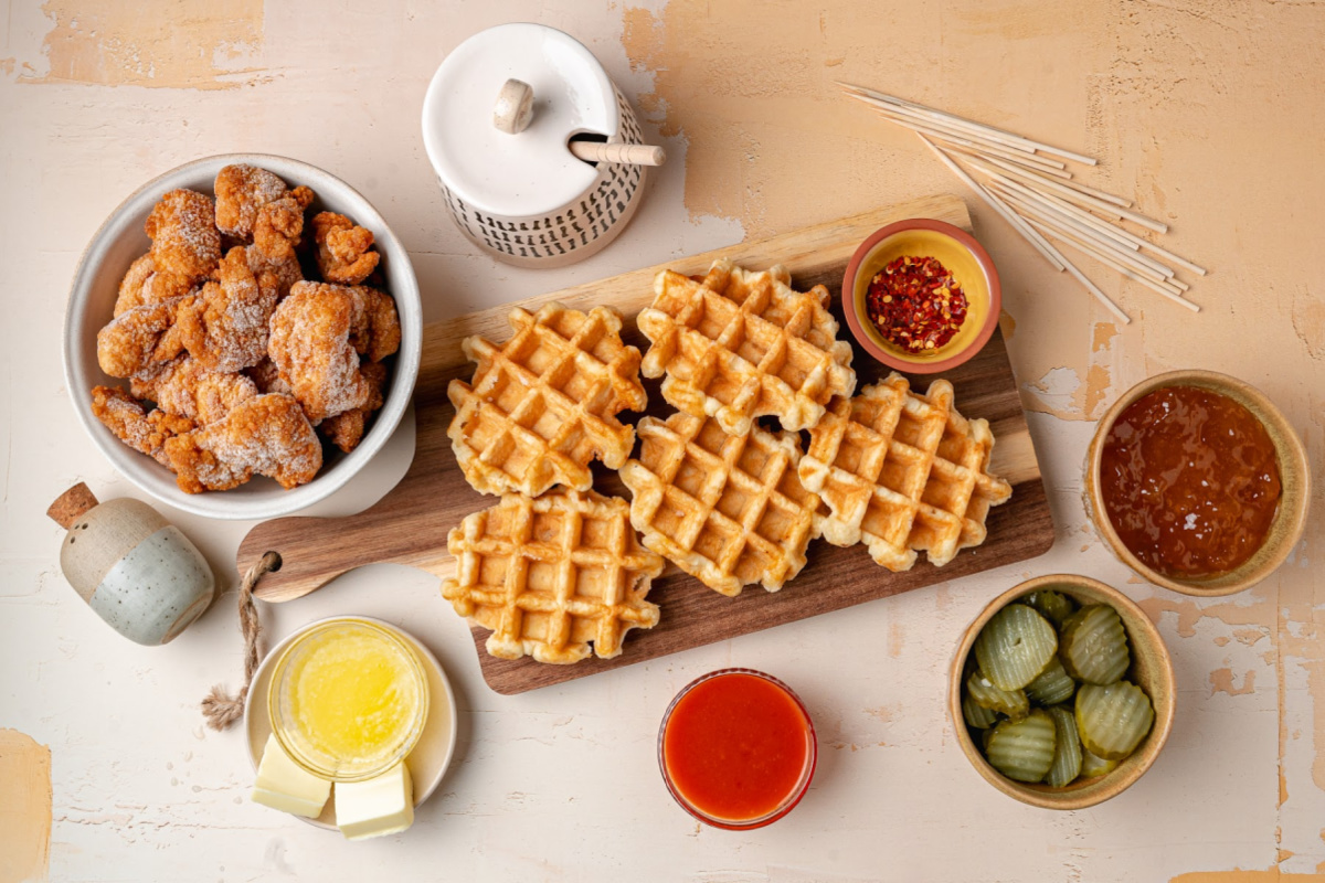 Hot Honey Peach Chicken and Waffle Bites Ingredients Ingredients for hot honey peach chicken and waffle bites including Liege waffles, popcorn chicken, dill pickles, peach preserves, hot sauce, and red pepper flakes.