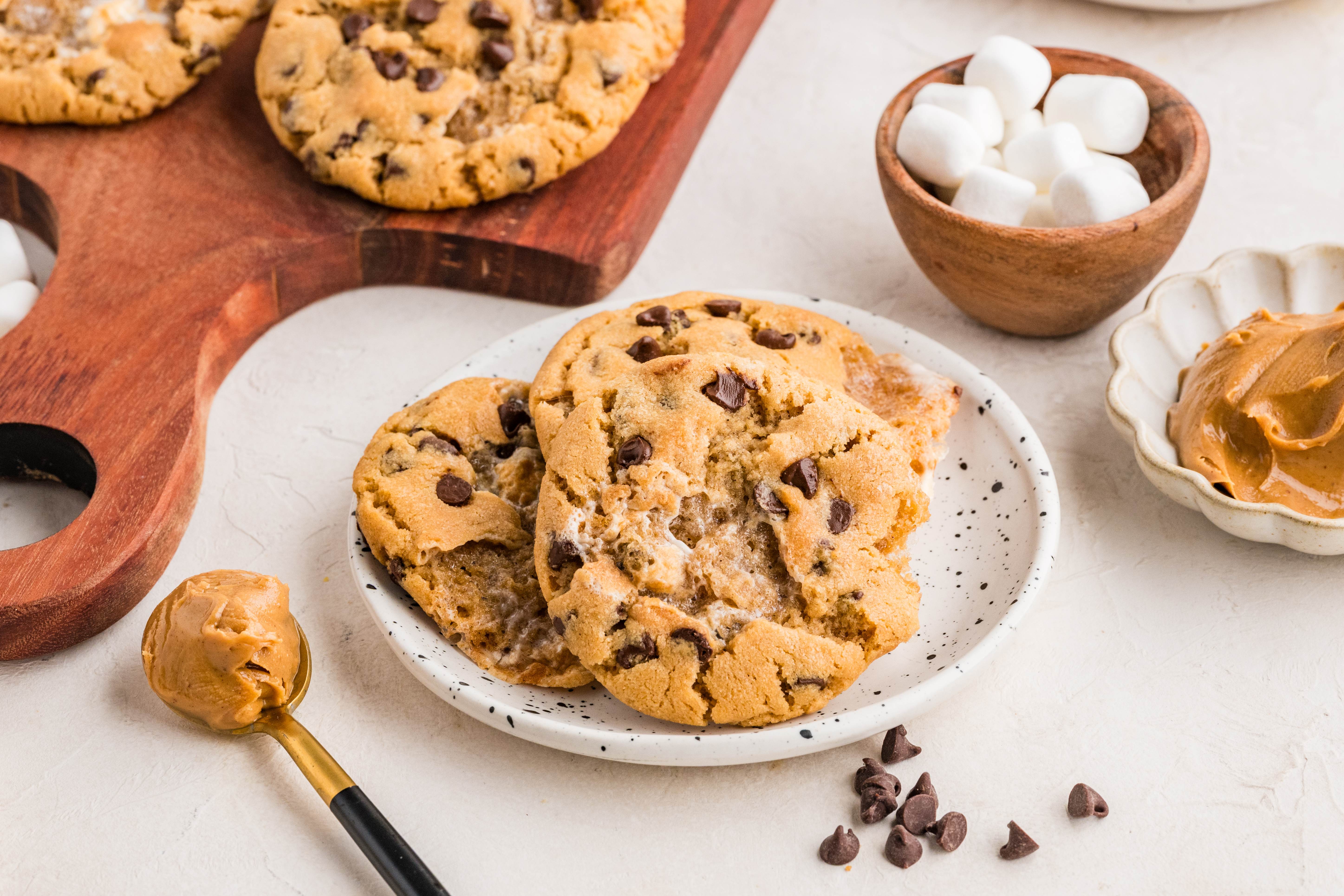 Toasted Marshmallow Peanut Butter Cookies Soft peanut butter cookies with toasted marshmallow pockets and mini chocolate chips stacked on a white plate.