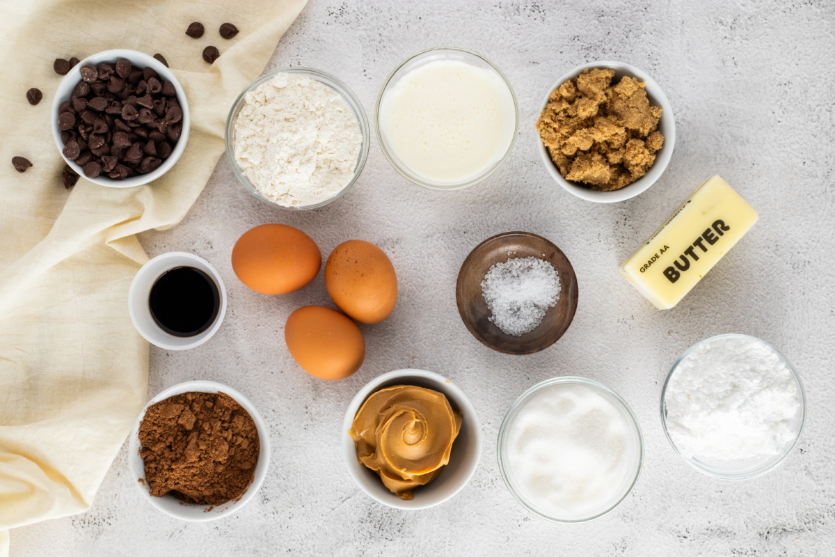 Ingredients for layered Buckeye brownies including peanut butter, chocolate chips, cocoa powder, and butter