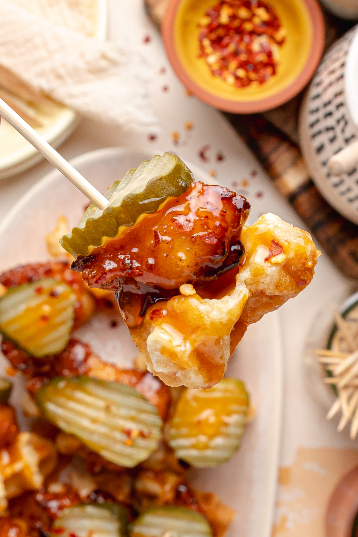 Chicken and Waffle Bites Close-Up Chicken and waffle bites with peach hot honey glaze and dill pickle chips served on a toothpick.