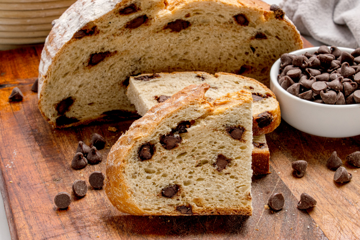Chocolate Chip Artisan Bread sliced on a wooden board with visible chocolate chips and crusty exterior
