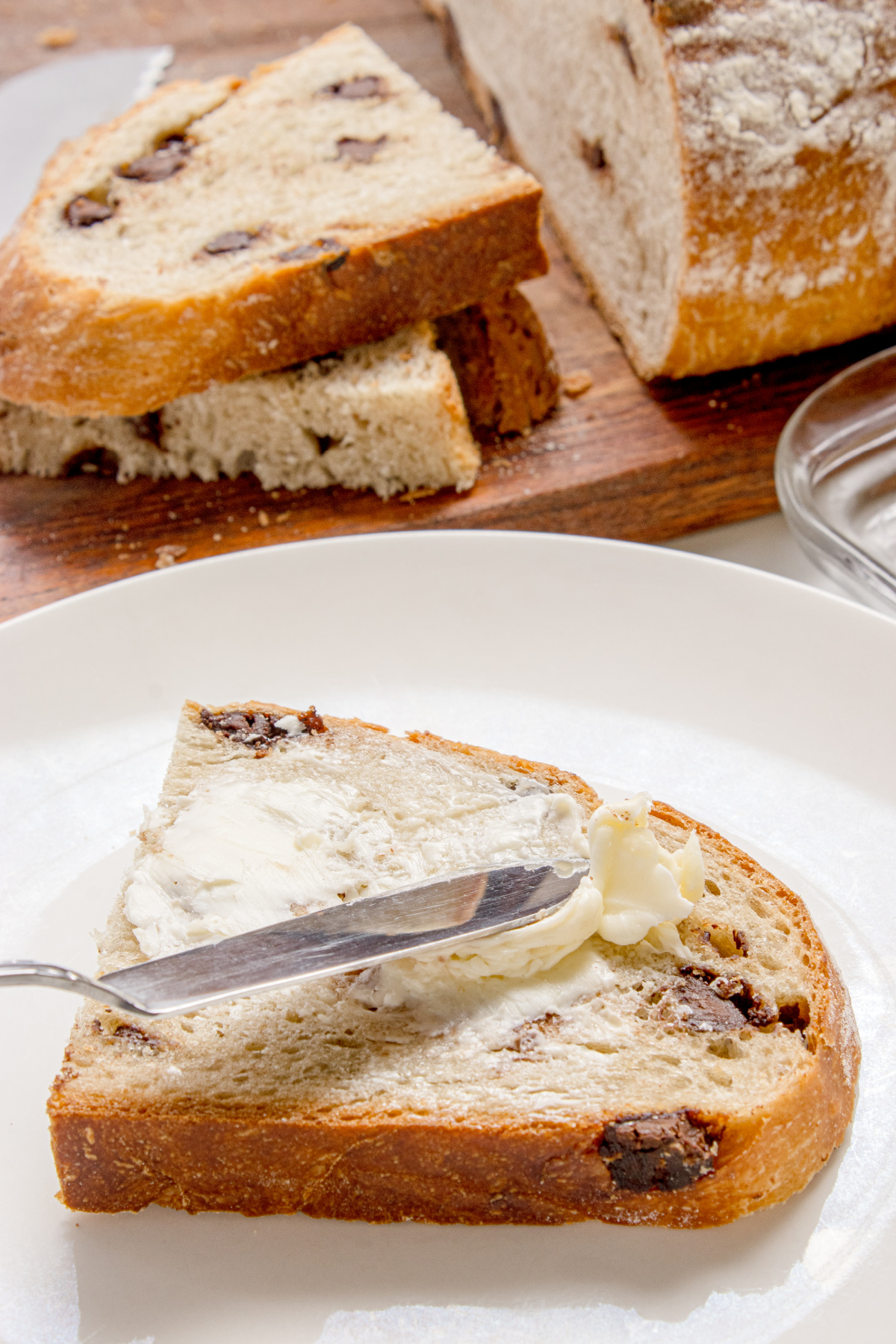 slice of chocolate chip bread with butter spread on top on a plate