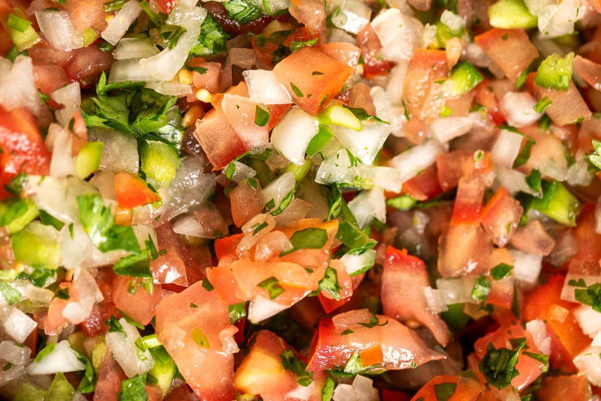 Close-up texture of homemade pico de gallo with seeded tomatoes and jalapeño Close-up of chunky homemade pico de gallo with diced tomatoes, onion, jalapeño, cilantro, and lime juice