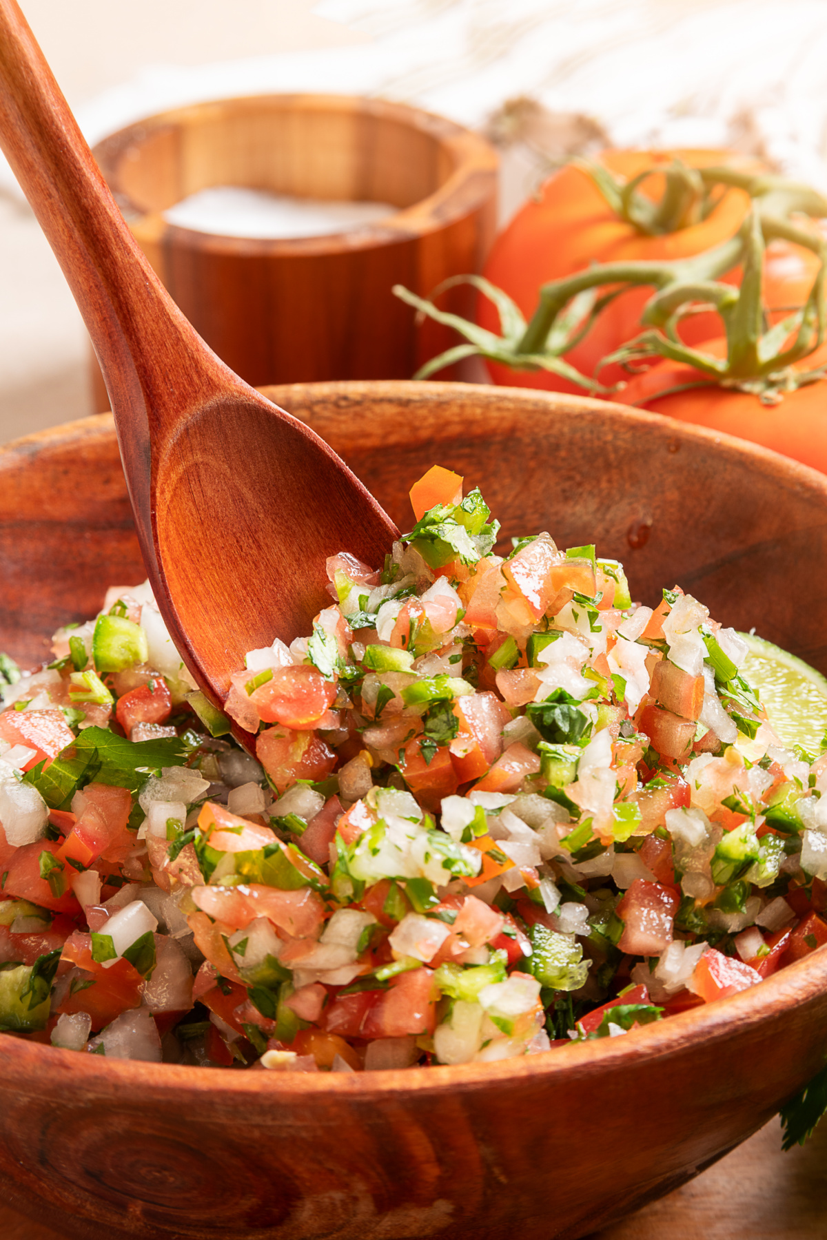 Fresh chunky pico de gallo ready for tacos and tortilla chips Serving spoon scooping chunky pico de gallo with tomatoes, onion, jalapeño, cilantro, and lime