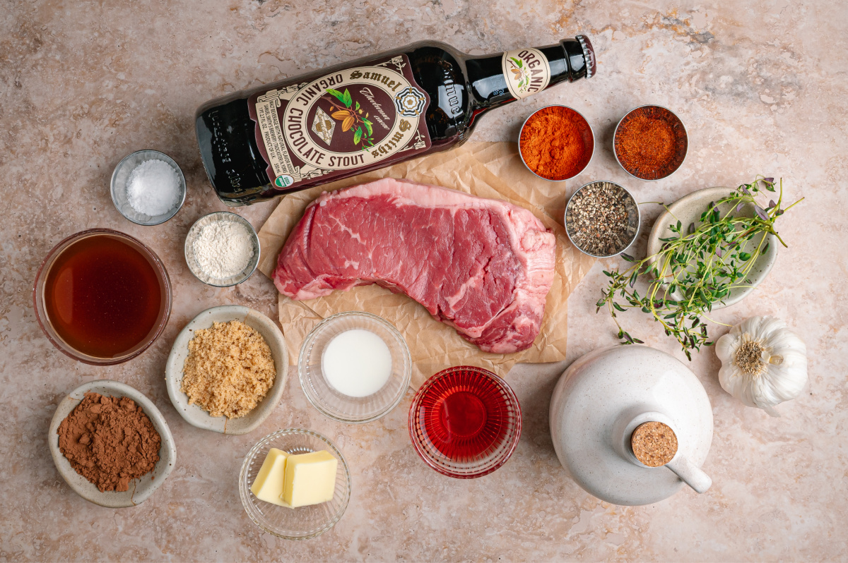 Ingredients for cocoa rubbed steak including New York strip steak, cocoa powder, chocolate stout, spices, and beef broth.
