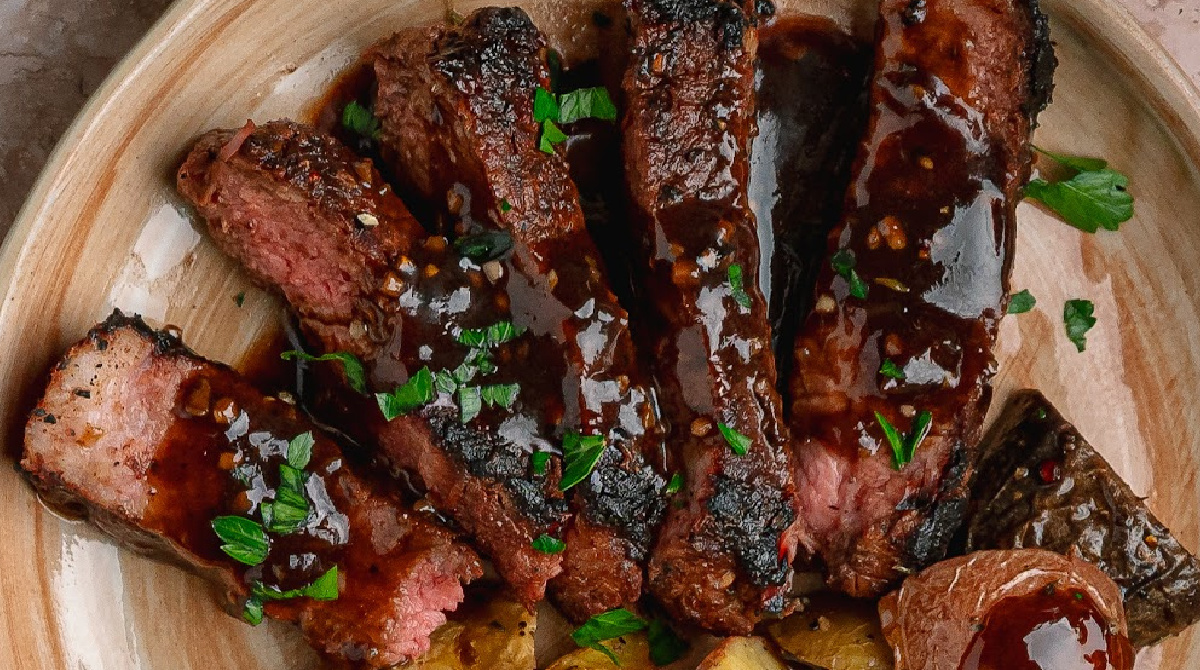Cocoa rubbed steak with dark stout pan sauce sliced and covered in dark savory pan sauce.