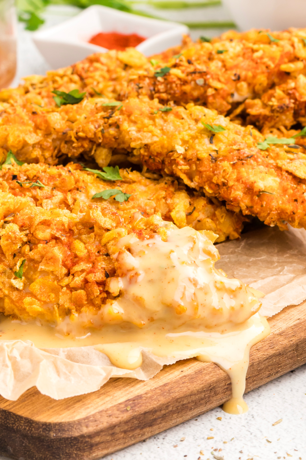 Cornflake Crusted Chicken Tenders with thick crispy cornflake coating and homemade honey mustard dripping across the front tender