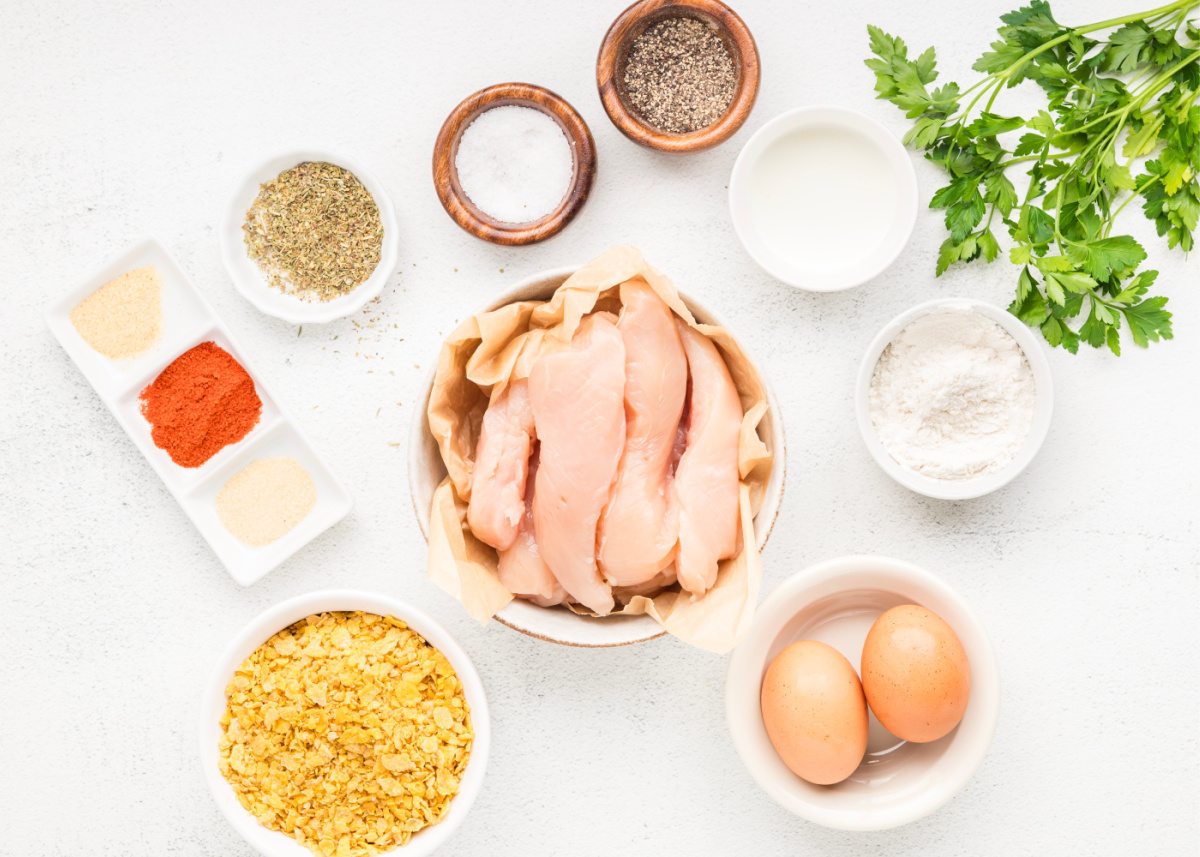 Ingredients for Cornflake Crusted Chicken Tenders including chicken tenders, crushed cornflakes, eggs, flour, and seasonings