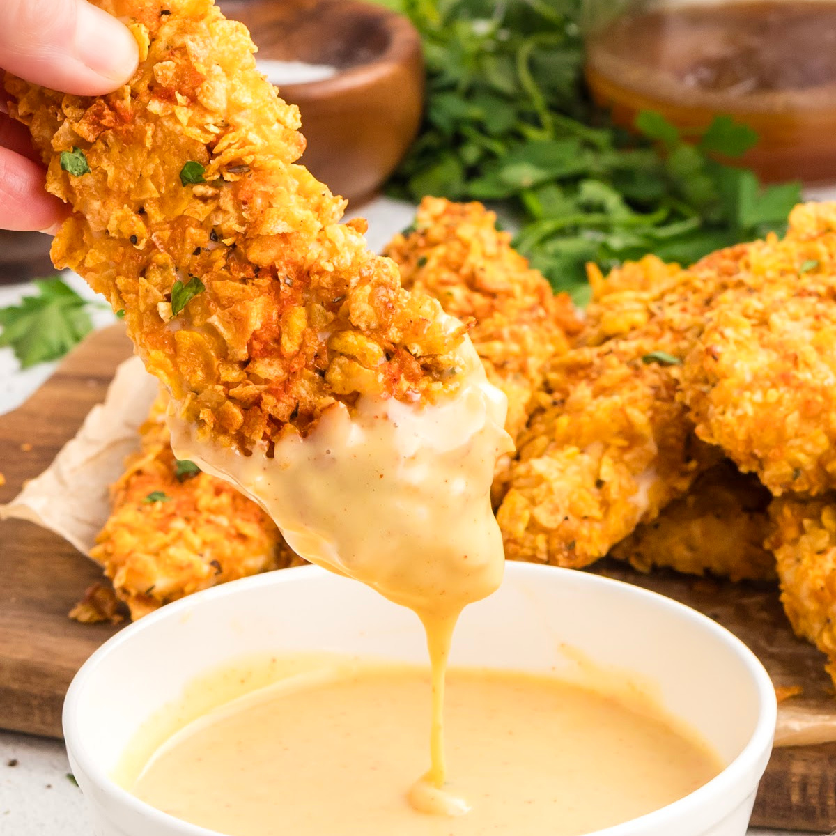 Cornflake Crusted Chicken Tenders dipped in creamy honey mustard sauce with crunchy cornflake coating