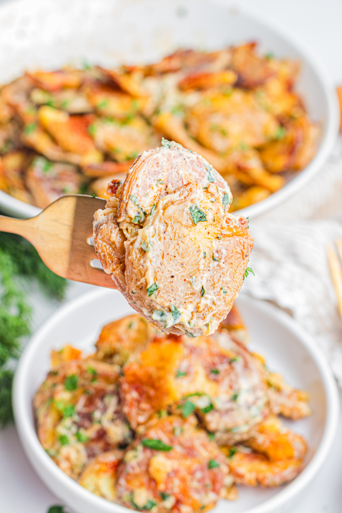 Fork holding Crispy Smashed Potato Salad with creamy lemon herb dressing, roasted baby potatoes, fresh herbs, and crispy potato edges