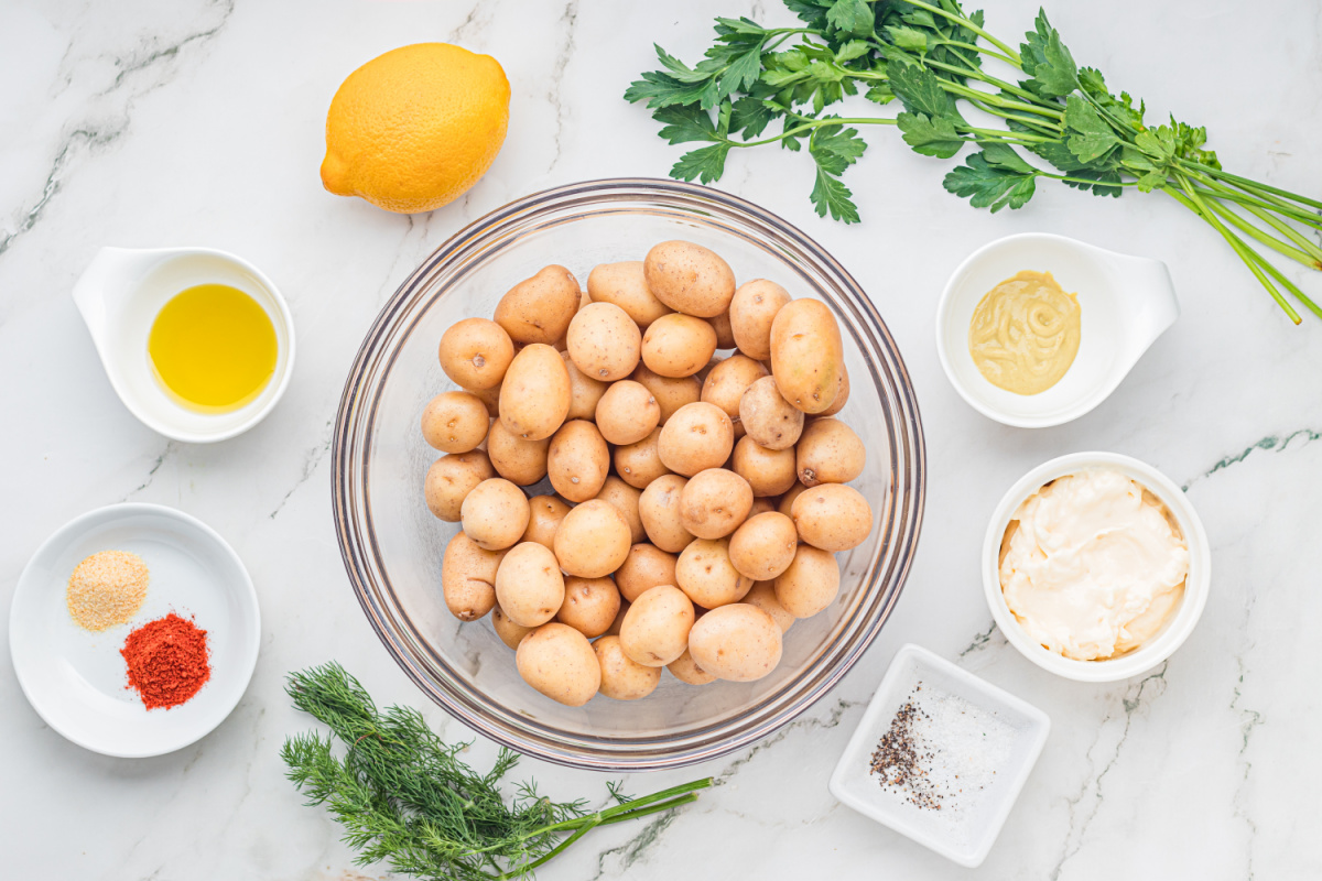 Ingredients for Crispy Smashed Potato Salad including baby potatoes, fresh dill, parsley, lemon, mayonnaise, Dijon mustard, olive oil, paprika, and garlic powder