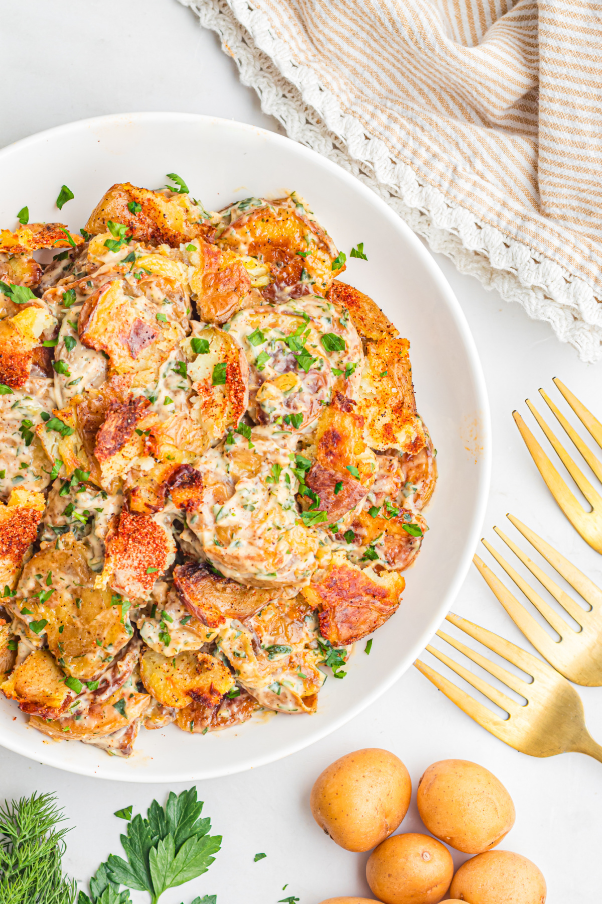 Overhead view of Crispy Smashed Potato Salad with roasted baby potatoes, creamy lemon herb dressing, fresh parsley, dill, and crispy golden edges