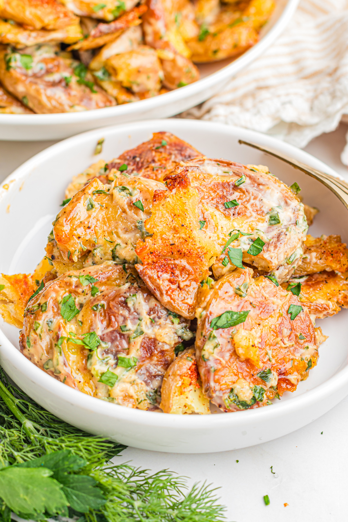 Plated Crispy Smashed Potato Salad with creamy lemon herb dressing, roasted baby potatoes, crispy golden edges, fresh dill, and parsley