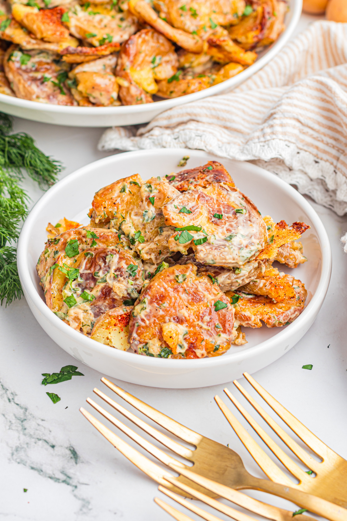 Serving of Crispy Smashed Potato Salad with roasted baby potatoes, creamy lemon herb dressing, crispy edges, and fresh parsley in a white bowl
