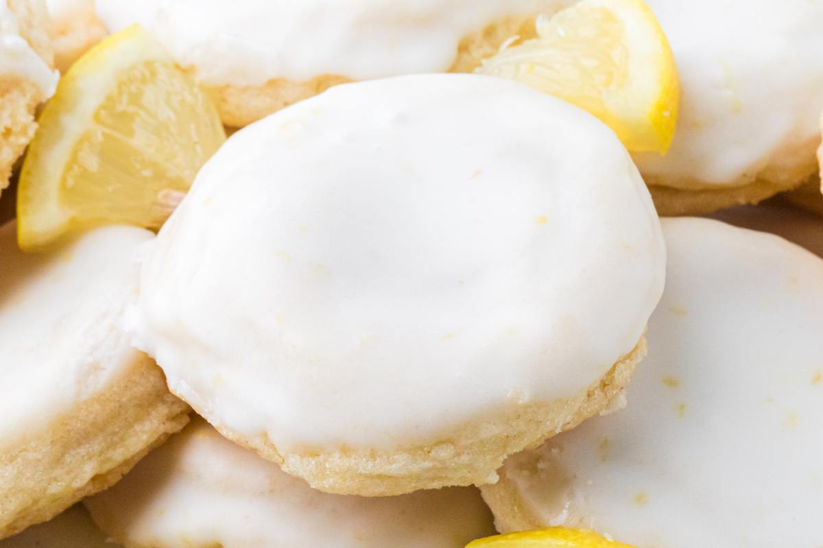 Glazed lemon sugar cookies topped with thick lemon glaze and surrounded by fresh lemon wedges