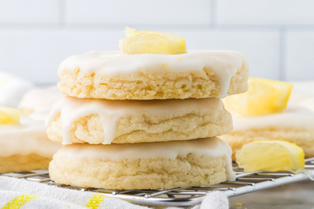 Glazed lemon sugar cookies stacked on a cooling rack showing their soft centers and thick lemon glaze