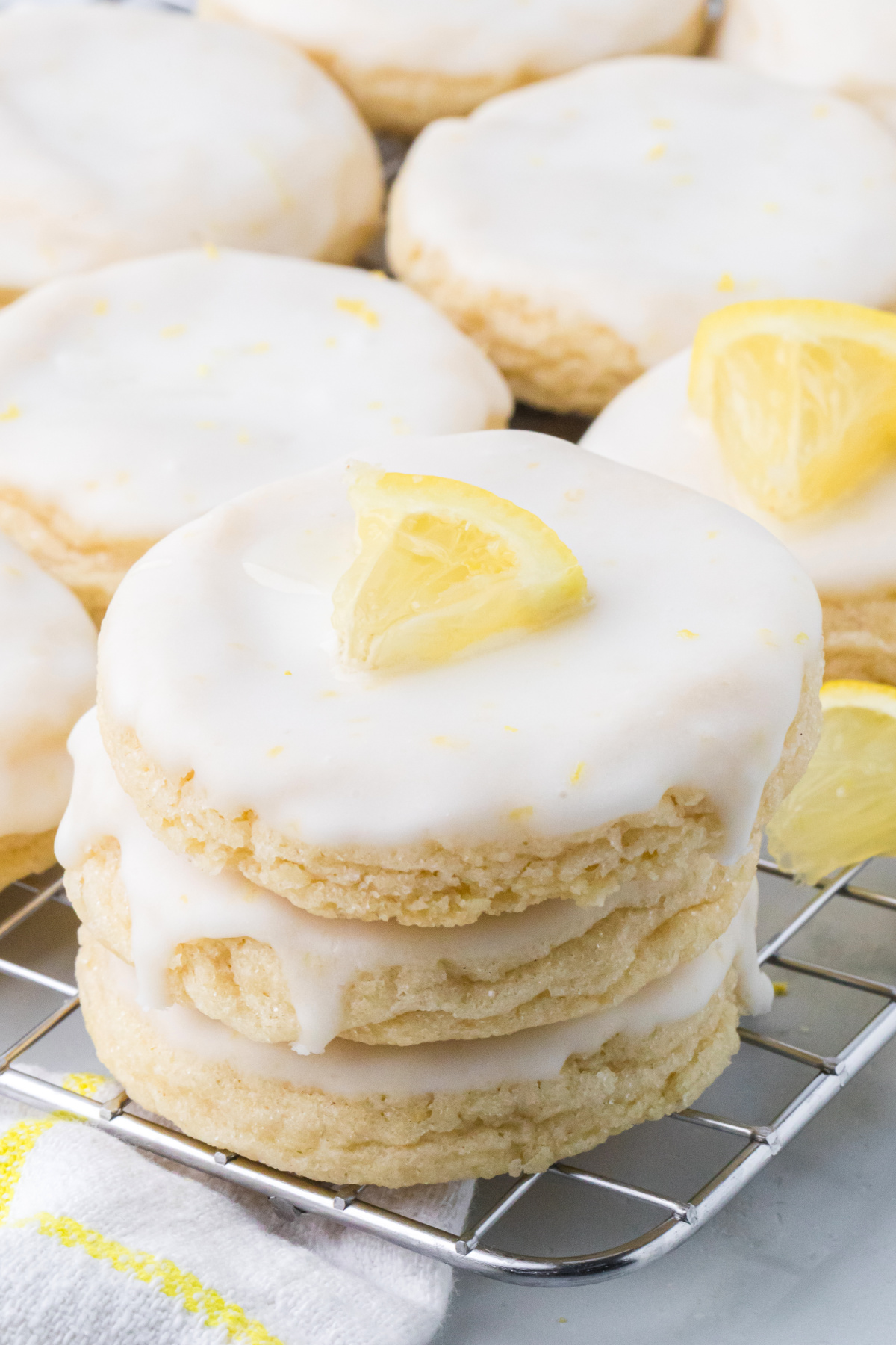 Glazed lemon sugar cookies stacked on a cooling rack with thick lemon glaze