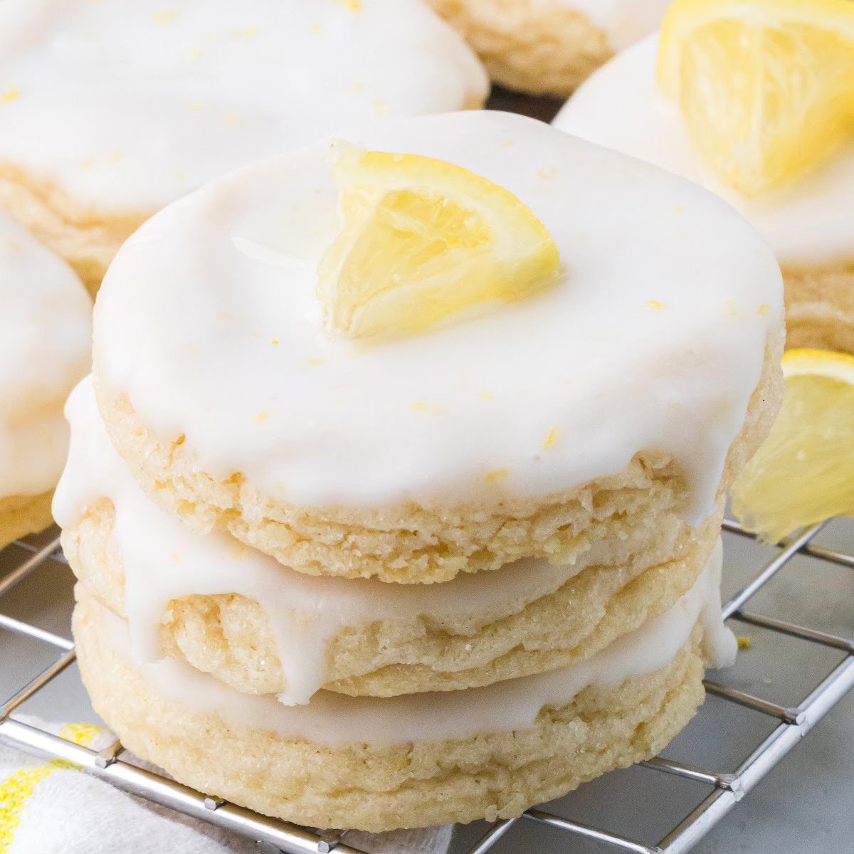 Glazed lemon sugar cookies with thick lemon glaze stacked on a cooling rack