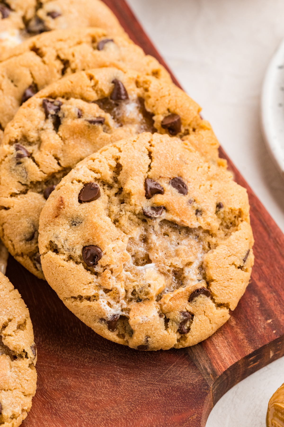 Thick and Chewy Peanut Butter Cookies Thick peanut butter cookie with toasted marshmallow pockets and mini chocolate chips on a wooden serving board.