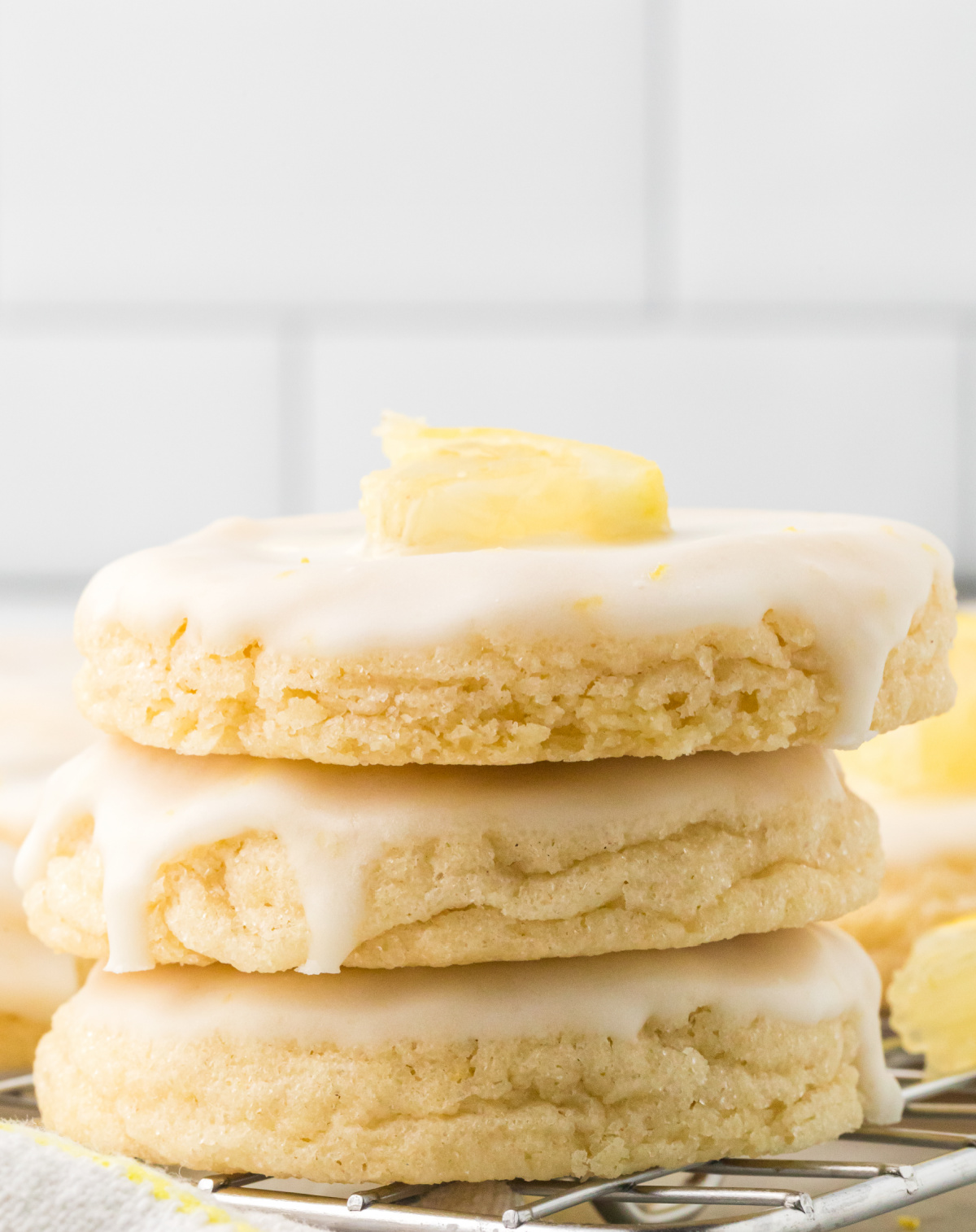 Homemade lemon cookies stacked on a cooling rack showing their soft texture and lemon glaze