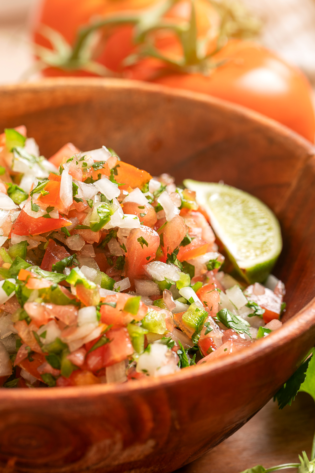 Chunky homemade pico de gallo made with seeded tomatoes and fresh lime juice Homemade pico de gallo with seeded tomatoes, white onion, jalapeño, cilantro, and lime in a wooden bowl