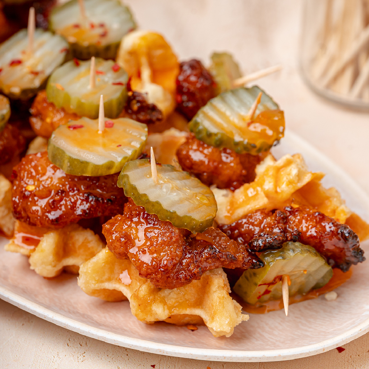 Hot Honey Peach Chicken and Waffle Bites topped with dill pickle chips and peach hot honey glaze.