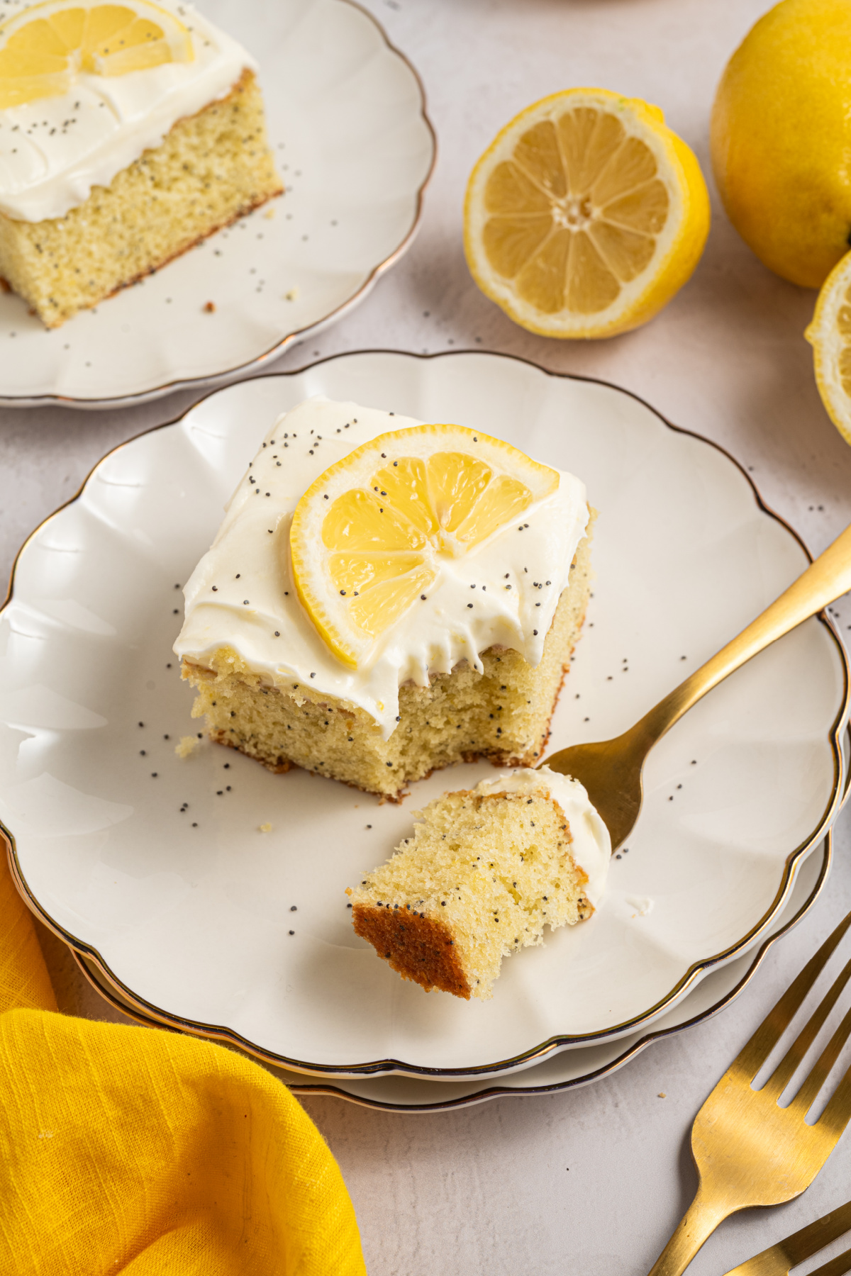 Lemon poppy seed cake with cream cheese frosting on a plate with a bite taken and a fork holding a piece