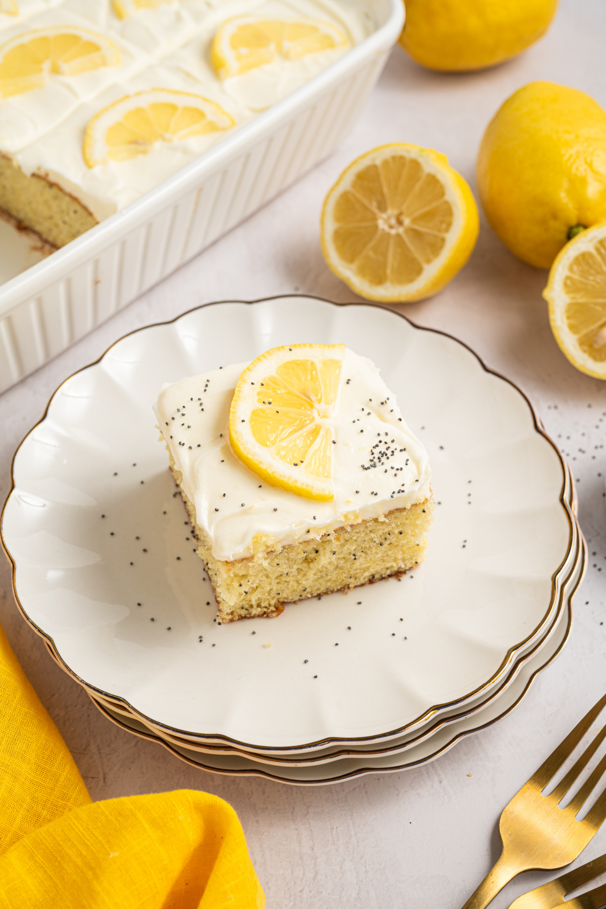 Lemon poppy seed cake with cream cheese frosting served on a white plate with lemon slice garnish