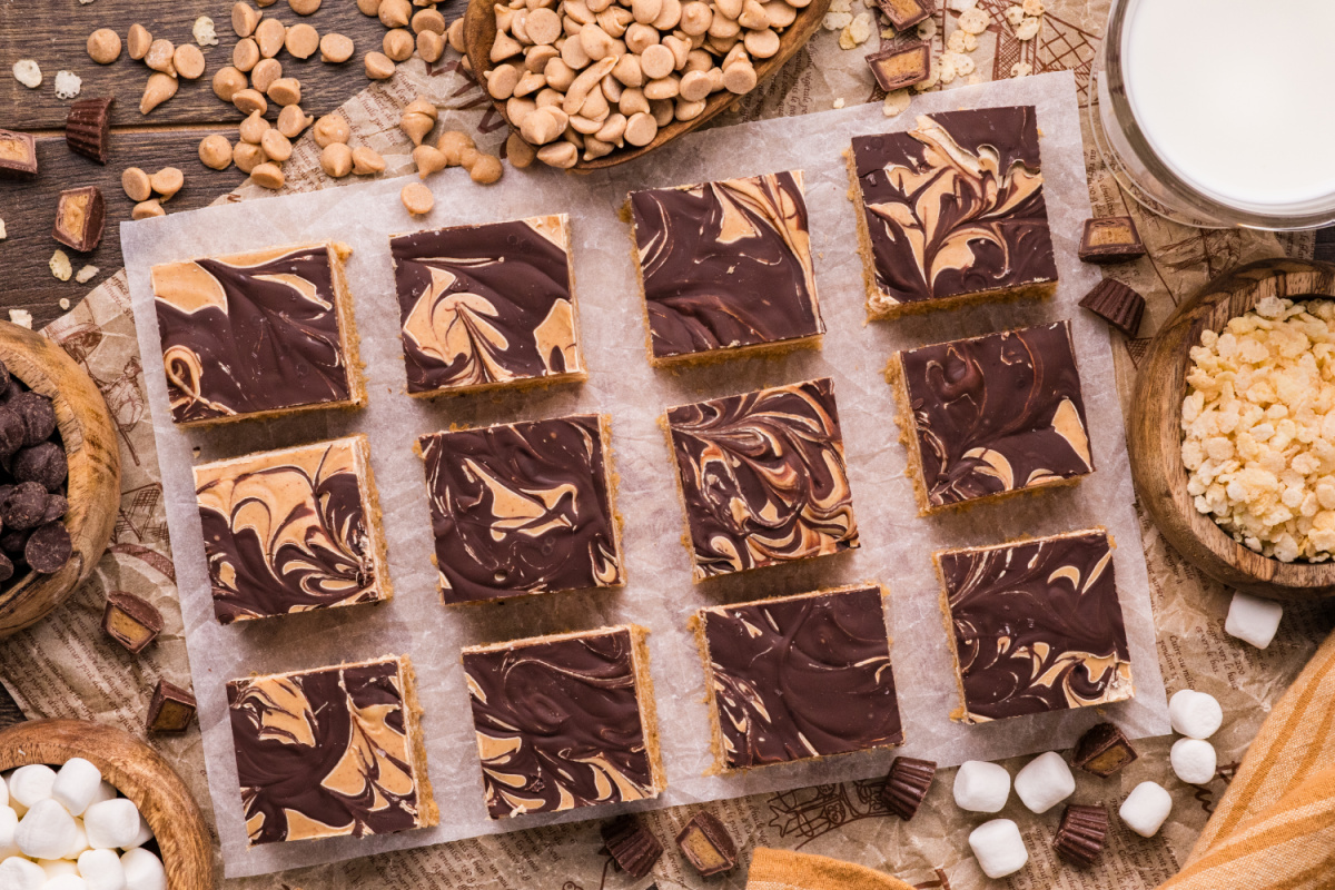 Overhead view of marbled peanut butter crunch bars with chocolate swirls, peanut butter chips, marshmallows, and puffed rice cereal