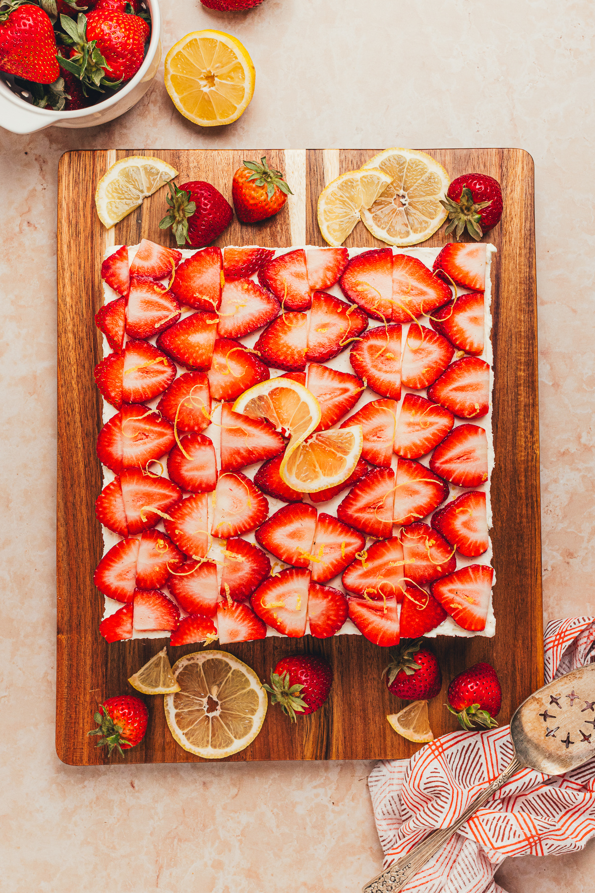 Overhead view of No-Bake Strawberry Lemon Icebox Cake topped with sliced strawberries, lemon zest, and mascarpone cream.