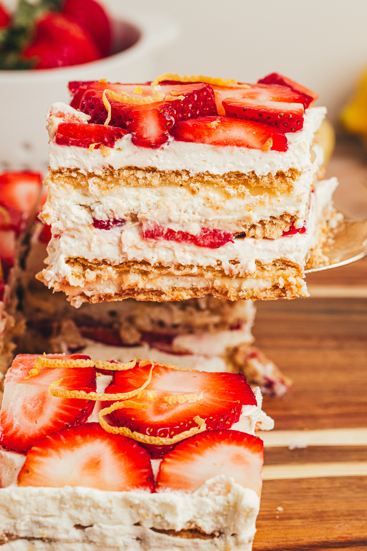 Lifted slice of No-Bake Strawberry Lemon Icebox Cake showing mascarpone cream, lemon curd, strawberries, and softened graham cracker layers.