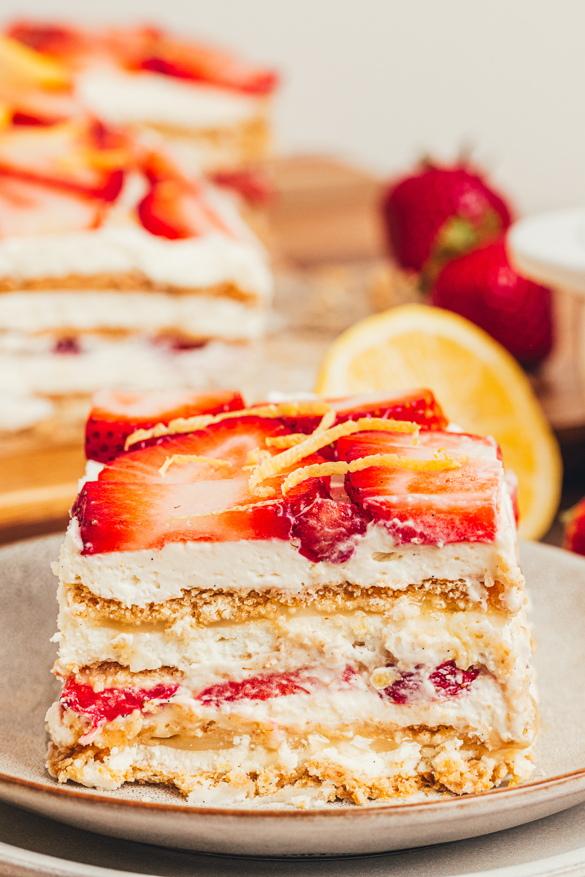 Slice of No-Bake Strawberry Lemon Icebox Cake with mascarpone whipped cream, lemon curd, graham cracker layers, and fresh strawberries.