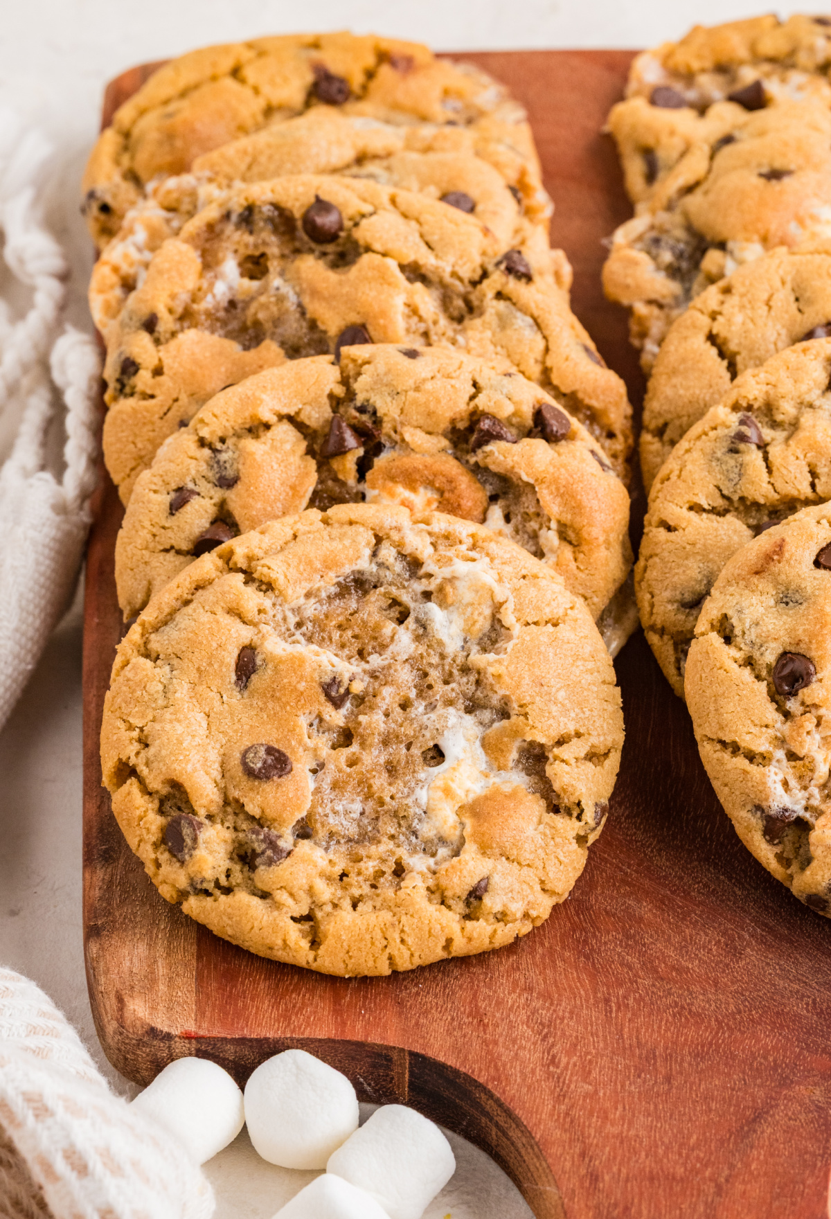Bakery-Style Peanut Butter Marshmallow Cookies Peanut butter marshmallow cookies on a wooden serving board with toasted marshmallow pockets and mini chocolate chips.
