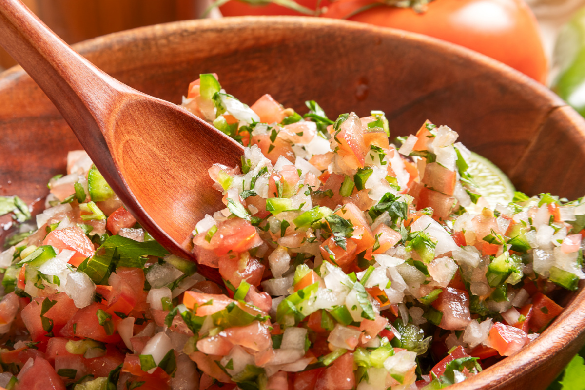Chunky pico de gallo with fresh lime, cilantro, and jalapeño Close-up of chunky pico de gallo with diced tomatoes, onion, jalapeño, cilantro, and a wooden serving spoon