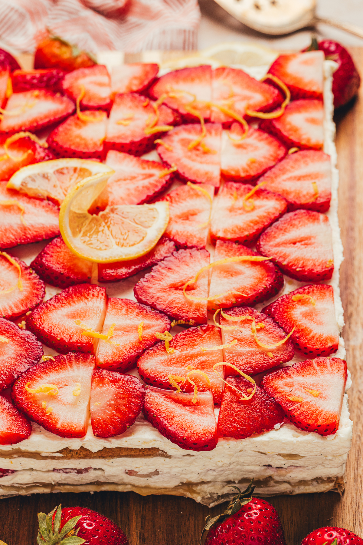 Close view of strawberry lemon icebox cake topped with sliced strawberries, lemon zest, and mascarpone cream layers.